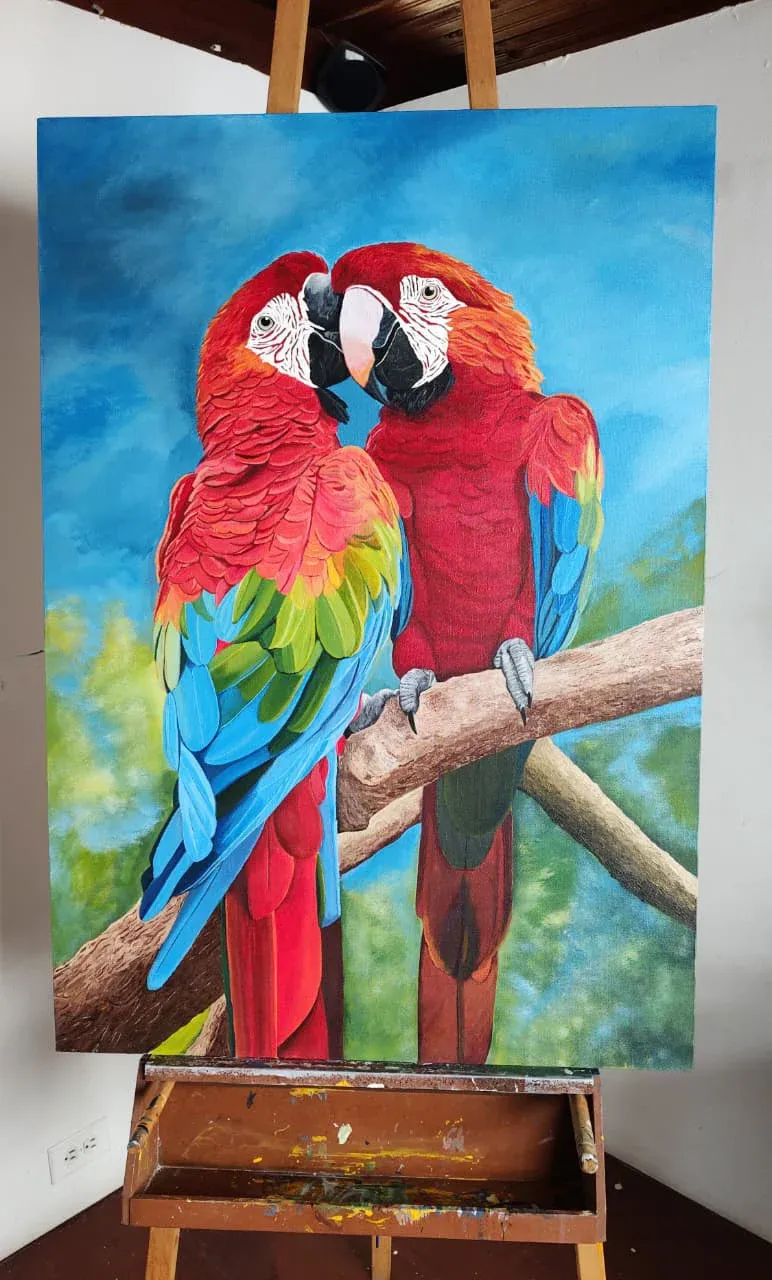 Pareja de guacamayas rojas posadas en una rama sobre fondo azul